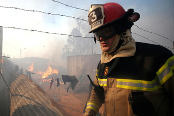 Un bombero camina cerca de una vivienda en llamas en los incendios en Valparaíso, el 24 de diciembre de 2019. Rodrigo Garrido / Reuters 350 Incendio Ramaditas2